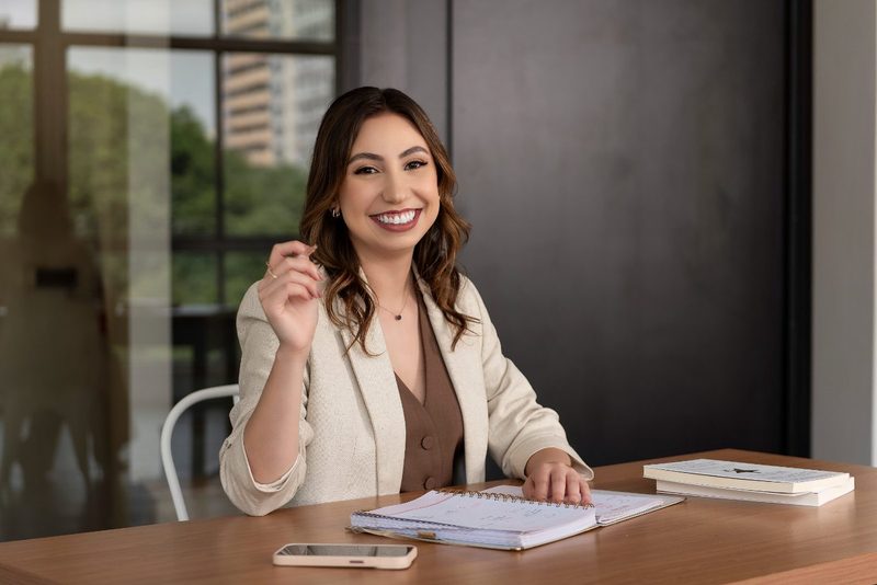 Gabriela Leopoldino sorrindo, em uma mesa de trabalho